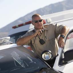 A police officer using his cruiser's two-way radio.